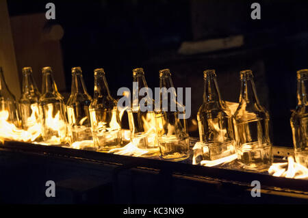 Anlage zur Herstellung von Glasflaschen. Glasflaschen auf einem Förderband mit Feuer Stockfoto