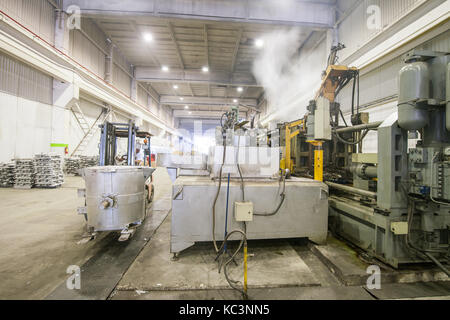 Gießen des Aluminium Metall von der Pfanne bis zum Beladen der Maschine in einem großen Behälter Stockfoto