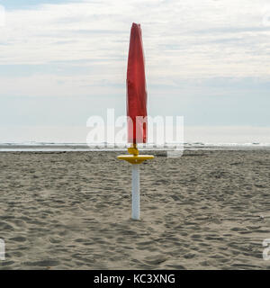 Ein Regenschirm geschlossen am Strand am Ende des Sommers Stockfoto
