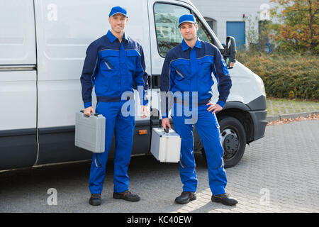 Volle Länge Portrait von zuversichtlich Techniker gegen Fahrzeug auf der Straße Stockfoto