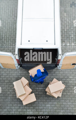 Direkt oberhalb der Schuß des Delivery Man entladen Kartons von Van auf der Straße Stockfoto