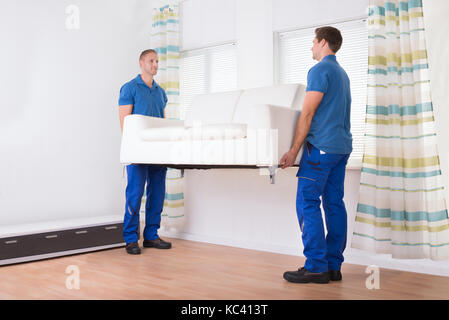 Volle Länge des Young movers Sofa zu Hause tragen Stockfoto