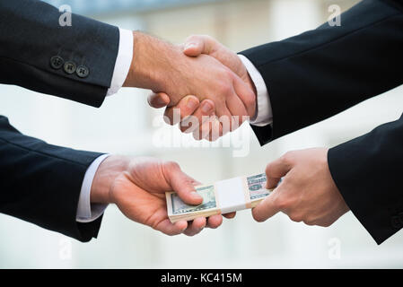 Zugeschnittenes Bild des Geschäftsmannes zitternden Hand während Bestechung Partner im Freien Stockfoto