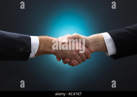 Nahaufnahme der Unternehmer die Hände schütteln vor blauem Hintergrund Stockfoto