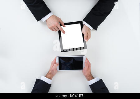 Zugeschnittenes Bild von Geschäftsleuten mit digitalen Tabletten am weißen Tisch im Büro Stockfoto