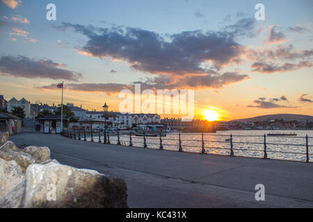 Eingang an der Promenade und der Seebrücke, die mit der untergehenden Sonne über Strand und Meer in der Ferne. Stockfoto