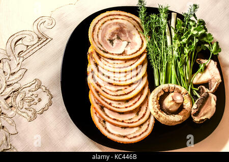 Runde scheiben Hackbraten mit geräuchertem Schweinefilet auf schwarze Platte Stockfoto