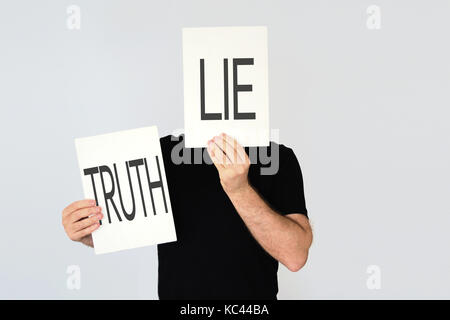 Mann mit zwei Karten mit den Worten Lüge und Wahrheit, die verschiedene Lüge. Dualität Konzept. Stockfoto