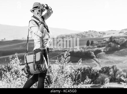 Entdecken Sie magische Ausblicke der Toskana. aktive Frau Wanderer mit Tasche auf der Toskana Wanderung unter Foto mit Vintage Foto Kamera Stockfoto