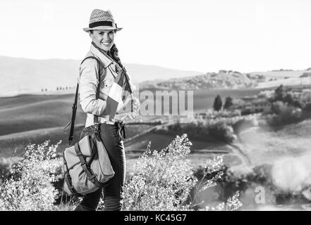 Entdecken Sie magische Ausblicke der Toskana. Portrait von glücklich aktive Frau Wanderer in Hut mit italienischer Flagge wandern in der Toskana Stockfoto