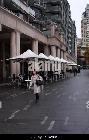 Eine junge Frau in einem Mantel entlang einer ruhigen Straße in Sydney Stockfoto