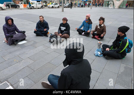 Manchester, Großbritannien. 2. Okt 2017. Ein 'Meditation Flash Mob' ihre Zigarettenkippen auf dem kalten Pflaster außen John RYLAND's Library, Deansgate, Manchester, UK, um den Frieden in die Welt am zweiten Tag der Protest der konservativen Politik der Krieg gegen Unschuldige braun Männer, Frauen und Kinder weltweit zu bringen. Credit: Graham M. Lawrence/Alamy leben Nachrichten Stockfoto