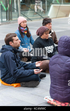 Manchester, Großbritannien. 2. Okt 2017. Ein 'Meditation Flash Mob' ihre Zigarettenkippen auf dem kalten Pflaster außen John RYLAND's Library, Deansgate, Manchester, UK, um den Frieden in die Welt am zweiten Tag der Protest der konservativen Politik der Krieg gegen Unschuldige braun Männer, Frauen und Kinder weltweit zu bringen. Credit: Graham M. Lawrence/Alamy leben Nachrichten Stockfoto