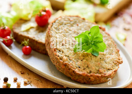 Nahaufnahme von einigen veggie Burger mit Auberginen und andere Gemüse in eine Platte gemacht, auf einem rustikalen Holztisch gelegt Stockfoto