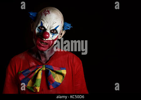 Nahaufnahme der Ein unheimlich bösen Clown tragen eine schmutzige und ausgefranster Kostüm mit einem leeren schwarzen Raum auf der rechten Seite Stockfoto