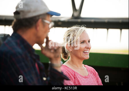 Eine junge weibliche Landwirt Gespräche mit ein mietling vor der überschrift zum Ernten von Weizen auf der Farm der Familie in Breckenridge, Colorado, wo sie wachsen Stockfoto