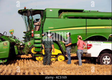 Eine junge weibliche Landwirt Gespräche mit angestellt, Hände, sowie eine GPS-Spezialist, vor der überschrift zum Ernten von Weizen auf der Farm der Familie in Breckenridge, n Stockfoto