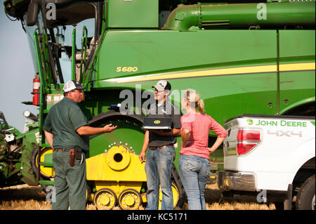 Eine junge weibliche Landwirt Gespräche mit angestellt, Hände, sowie eine GPS-Spezialist, vor der überschrift zum Ernten von Weizen auf der Farm der Familie in Breckenridge, n Stockfoto