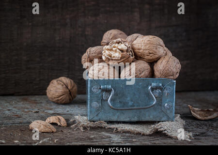 Walnüsse in einem kleinen eisernen Kasten und einer Leinwand Serviette. Holz- Hintergrund. Stockfoto