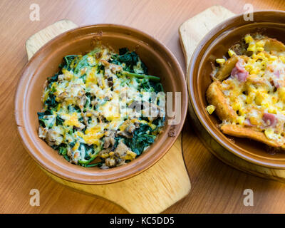 Spinat und Pilze in geschmolzenem Käse; Fleischbällchen in Sauce; Kartoffelecken mit Speck Stockfoto