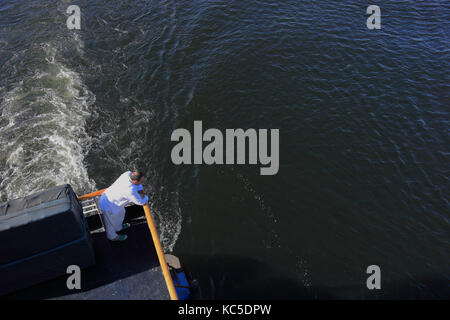 Der Mensch steht im Stern von einem Kreuzfahrtschiff und Suchen am Wasser Stockfoto