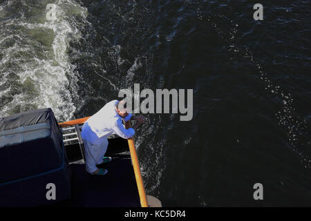 Der Mensch steht im Stern von einem Kreuzfahrtschiff und Suchen am Wasser Stockfoto