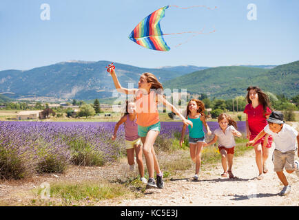 Große Gruppe von Alter - diverse Kinder Spaß flying rainbow Kite im Sommer Stockfoto