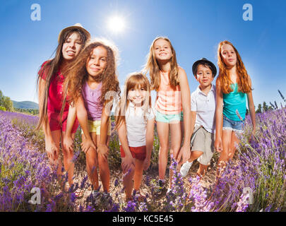 Gruppe der glückliche Zeit - verschiedene Kinder in lavendelfeld in einer Reihe und mit Blick auf die Kamera an einem sonnigen Tag Stockfoto