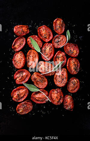 Ofen geröstet Tomaten mit Knoblauch und Kräutern auf einem Backblech Tomaten confit Vorspeise. Ansicht von oben. Stockfoto