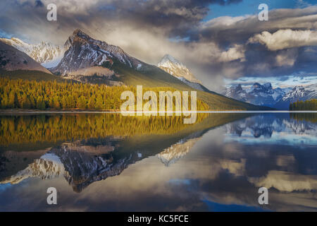 Berg und seine Reflexion Zeichnung als Pfeil in Maligne Lake mit dramatischen bewölkten Himmel. Kanada Landschaft. Spiegelbild. Stockfoto