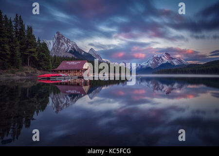 Haus und Boote in Maligne Lake, nach Sonnenuntergang. Feder an der Kanadischen Rockies. Kanada Landschaft. Spiegelbild. Stockfoto