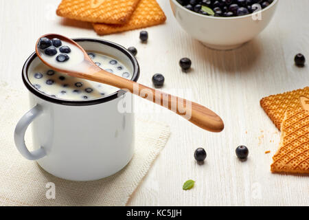 Die Tasse Milch mit Heidelbeeren und Cookies auf weißen Tisch Stockfoto