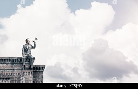 Unternehmer oder Manager auf dem Dach des Gebäudes etwas verkünden in Stockfoto