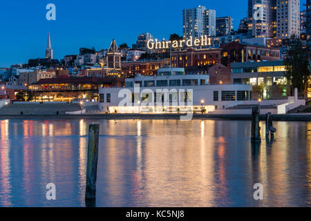 Der Ghirardelli Square Zeichen an dusck und die Skyline von San Francisco. Stockfoto