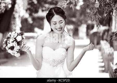 Junge und schöne asiatische Braut mit Blumenstrauß in der Hand, Schwarz und Weiß. Stockfoto