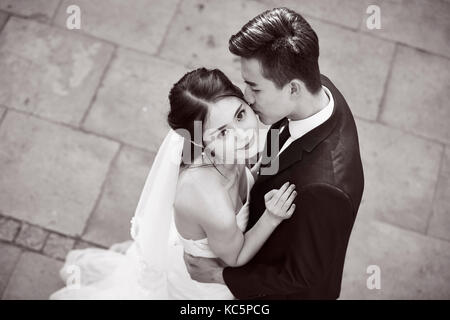 Junge asiatische Braut und Bräutigam umarmen Küssen tanzen in Open Air, Hohe Betrachtungswinkel, Schwarz und Weiß. Stockfoto