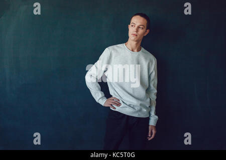 Junger Mann in grauen Sweatshirt auf schwarzem Hintergrund. Mock-up. Stockfoto