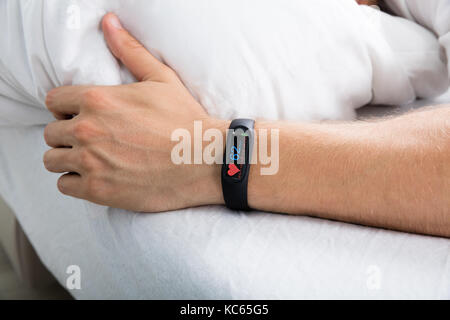 Fitness Tracker mit Heartbeat Rate auf der Mann mit der Hand über das Bett Stockfoto