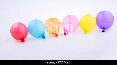 Bunte kleine Luftballons in Linie auf weißem Hintergrund Stockfoto