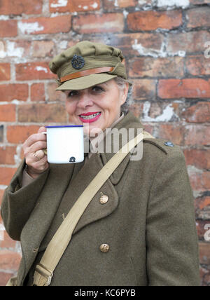 Dame in Vintage einheitliche Tee trinken der britischen Armee, der 1940 aus der Dose Tasse. Der Blairgowrie Großbritannien 40 Wochenende Stockfoto