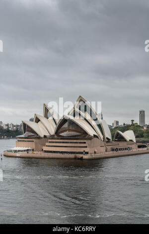 Sydney, Australien - 21. März 2017: Frontalansicht des Opera House unter braun-grauen regnerischen Himmel. Menschen auf der Plattform. Stockfoto