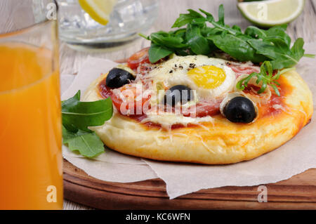 Mini Pizza mit Würstchen und Ei und Rucola für Frühstück Stockfoto