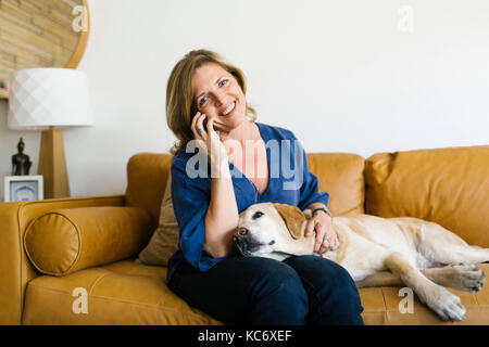 Frau streicheln Labrador Retriever und mit Handy Stockfoto