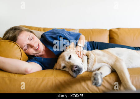 Frau und Labrador Retriever liegend auf dem Sofa Stockfoto
