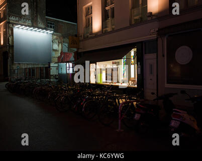 Leeres Café, nachts beleuchtet, Fahrradständer, große beleuchtete leere Plakate. Stockfoto