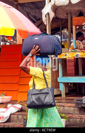 Frau an Grenadas St. George's Marktplatz trägt schwere Tasche auf den Kopf, Grenada und die Grenadinen Stockfoto