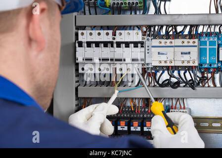 Männliche Elektriker Arbeiten auf Sicherungskasten mit Schraubendreher Stockfoto