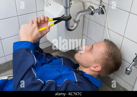 Junge männliche Klempner Instandsetzung Spülbecken in der Küche Stockfoto