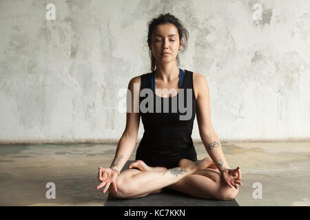 Junge attraktive Frau in padmasana darstellen, studio Wand Hintergrund Stockfoto