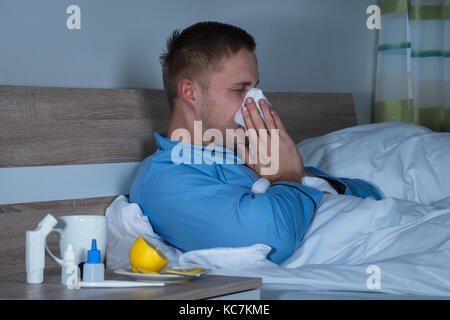 Junger Mann angesteckt mit Wechselbäder seine Nase in Taschentuch Stockfoto